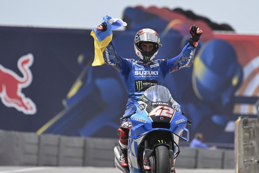 Pebalap tim Suzuki Alex Rins merayakan keberhasilannya merebut podium kedua dengan putaran kemenangan sambil membawa bendera Ukraina dan menyerukan perdamaian, pada MotoGP seri Amerika Serikat di Sirkuit Amerika, Austin, Texas, AS, Minggu (10/4/2022). 
