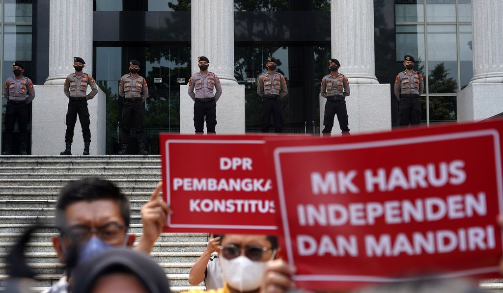 Polisi menjaga pintu Gedung Mahkamah Konstitusi, Jakarta saat para aktivis Indonesia Corruption Watch (ICW) dan beberapa perwakilan elemen masyarakat yang tergabung dalam Masyarakat Madani menggelar aksi seruan penyelamatan Mahkamah Konstitusi di halamannya, Selasa (4/10/2022). 