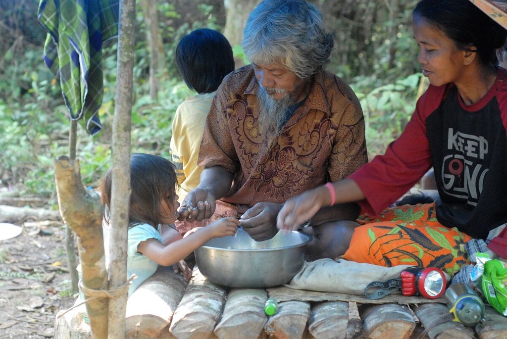 Warga menikmati makan seusai ritual memandikan anak di komunitas Orang Rimba di Taman Nasional Bukit Duabelas, Sarolangun, Jambi, Sabtu (2/7/2022).