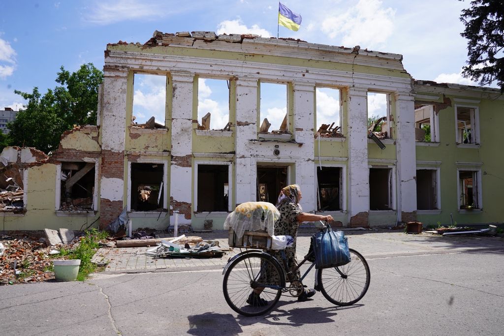 Warga melintas di depan sebuah reruntuhan gedung yang hancur terkena rudal Rusia di Okhtyrka, Provinsi Sumy, Ukraina, Minggu (22/6/2022). Okhtyrka merupakan salah satu wilayah yang dibombardir Rusia saat awal-awal perang. Kini, perbatasan wilayah tersebut dijaga ketat prajurit Ukraina. 