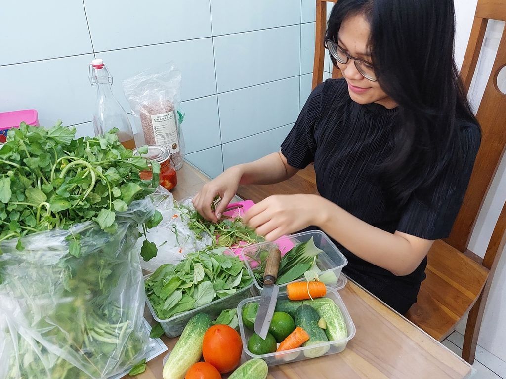 Yola Ayurveda membersihkan bahan-bahan untuk membuat <i>smoothies</i>, yang dibeli di Pasar Palmerah, Jakarta Pusat, Sabtu (18/6/2022). Setelah dibersihkan, sayuran dimasukkan ke dalam toples atau wadah untuk disimpan di kulkas. 