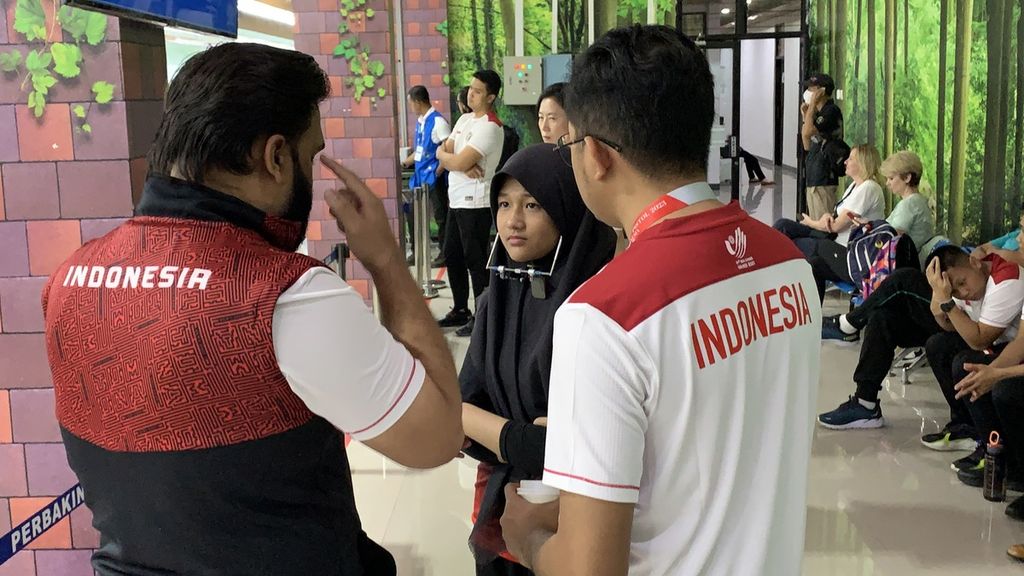 Pelatih tim pistol Indonesia, Abdul Qayyum Mohammed Omar Shah (kiri) memberikan arahan kepada seorang anggota tim pistol beregu putri, Rihadatul Asyifa (tengah) saat tampil di Piala Dunia Menembak Senapan dan Pistol ISSF 2023 di Jakarta, Rabu (1/2/2023).