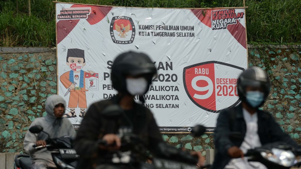 Warga melintasi baliho sosialisasi pelaksanaan Pilkada Kota Tangerang Selatan di Jalan Ciater, Serpong, Tangerang Selatan, Banten, Jumat (11/9/2020). 