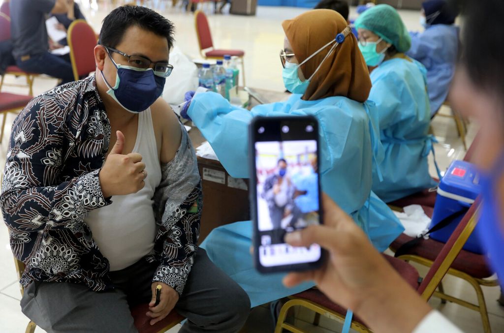 Tenaga kesehatan (nakes) memotret rekannya yang menerima suntikan vaksinasi penguat di sentra vaksin Gelanggang Remaja Pulogadung, Jakarta, Selasa (1/8/2022). 