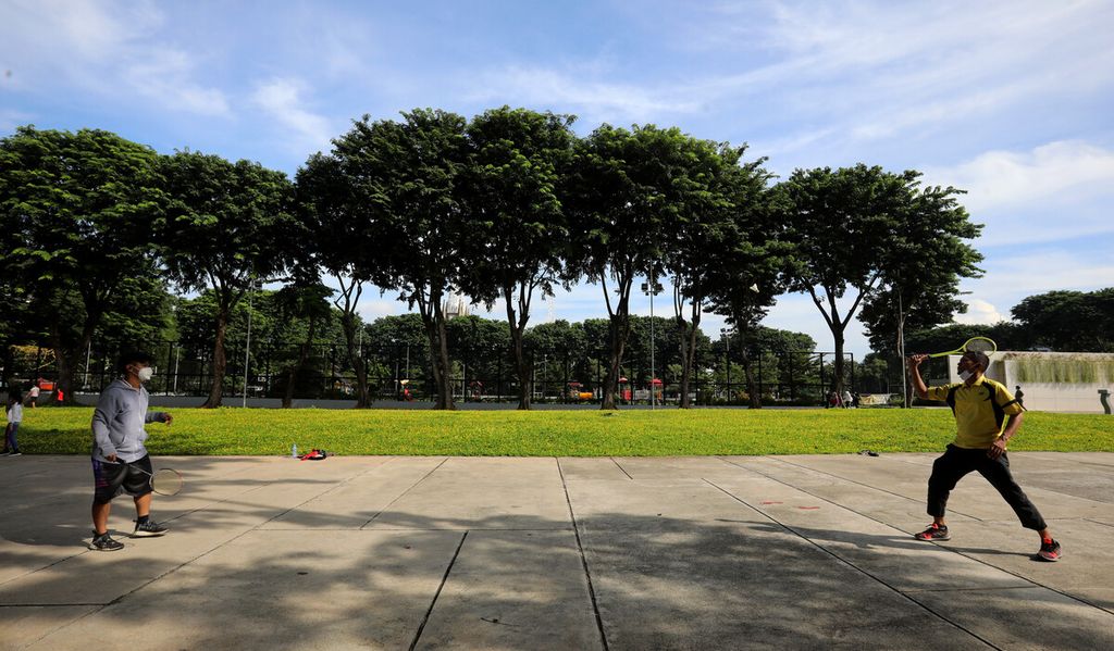 Pengunjung berolahraga badminton di kawasan Taman Lapangan Banteng, Jakarta Pusat, Minggu (14/3/2021). 