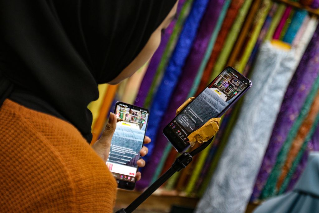 Seorang pedagang melakukan siaran langsung di media sosial untuk berpromosi di Pasar Cipadu, Tangerang, Kamis (3/11/2022). Kawasan Cipadu dikenal sebagai sentra perdagangan tekstil di Tangerang. 