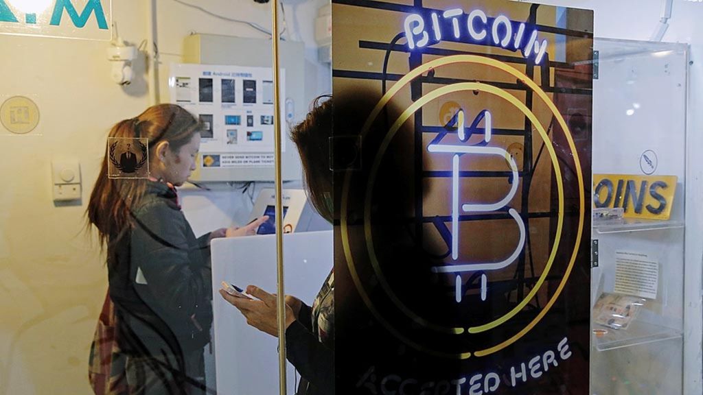 Bitcoin kini adalah salah satu mata uang maya yang populer. Tampak salah seorang warga Hong Kong menggunakan Bitcoin ATM di Hong Kong, Jumat (8/12/2017).