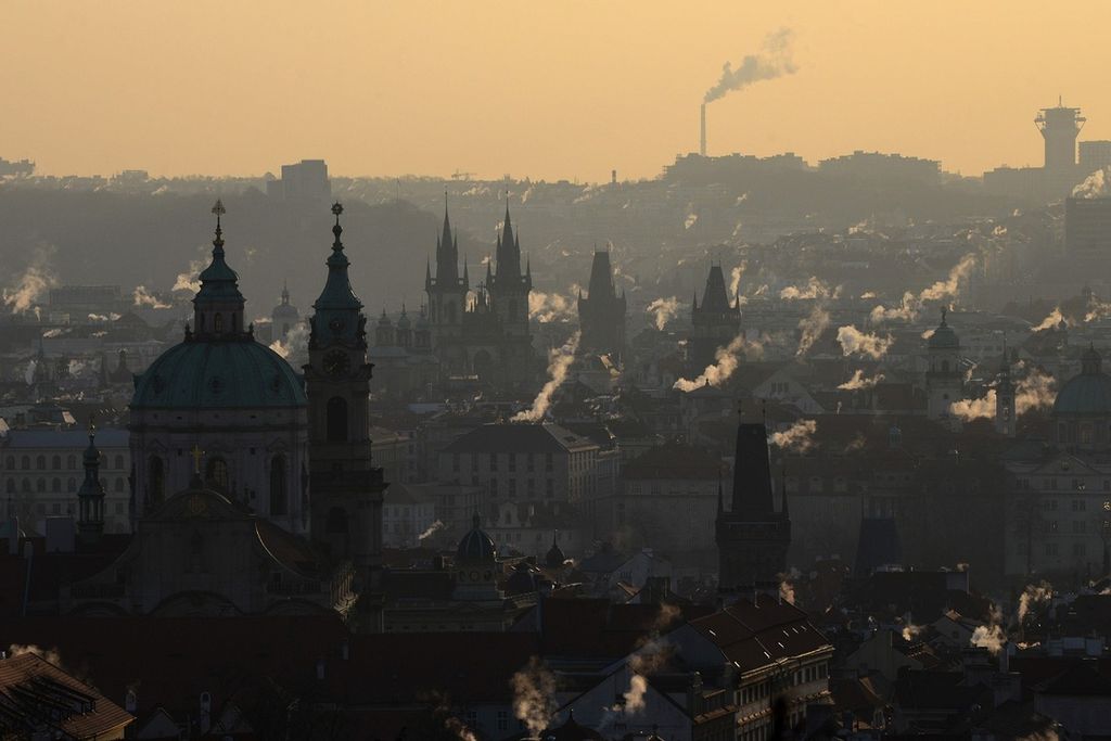 Asap membumbung dari atap gedung-gedung di Praha tengah central Prague, dengan pemandangan Gereja Saint-Nicolas (kiri), saat matahari terbit pada 26 Februari 2018.
