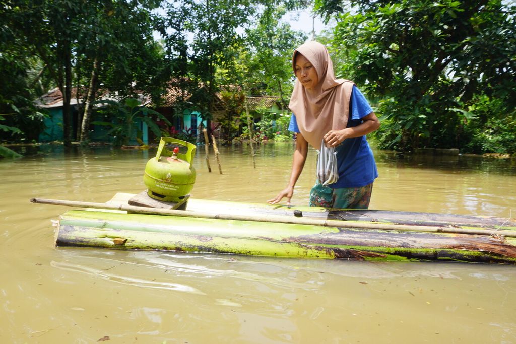 Banjir merendam Desa Nusadadi, Kecamatan Sumpiuh, Banyumas, Jawa Tengah, Jumat (18/3/2022). Sekitar 20 warga mengungsi ke tempat aman. Tampak seorang ibu sedang membeli gas di tengah banjir.