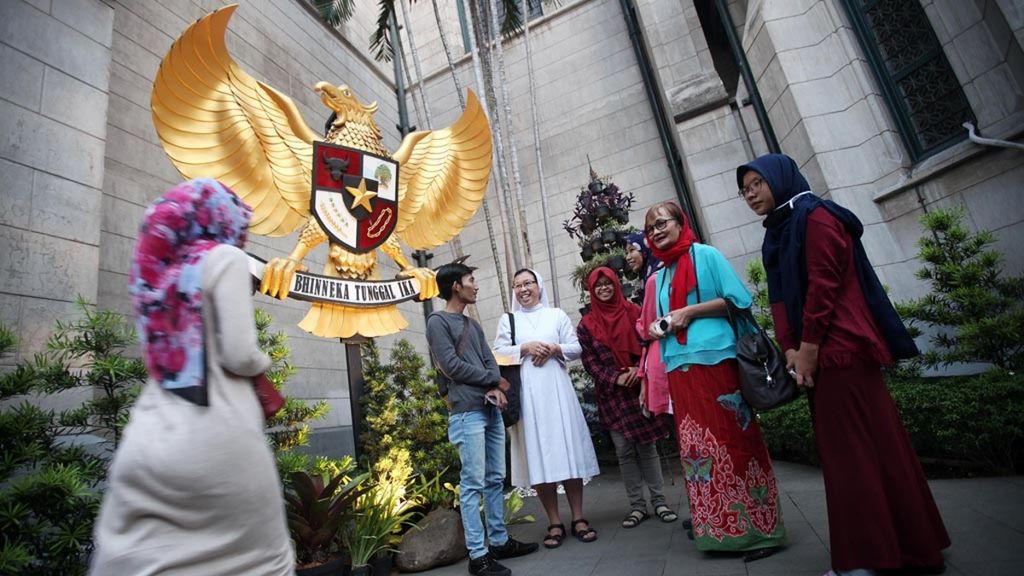 Umat lintas agama berbincang dekat patung Garuda Pancasila di Gereja Katedral, Jakarta, saat kumpul menjelang buka bersama lintas agama dengan tema ”Menguatkan Toleransi, Persaudaraan, dan Solidaritas Kemanusiaan”, Jumat (1/6/2018). Berkumpulnya umat lintas agama di saat Hari Lahir Pancasila ini menjadi salah satu bentuk nyata kuatnya kebersamaan lintas iman yang penting menguatkan persatuan dan kesatuan bangsa.