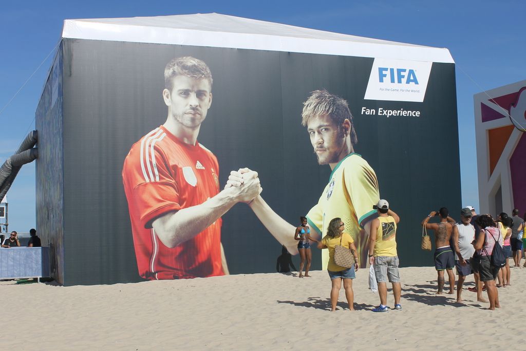 Suasana FIFA Fan Fest di kota Rio de Janeiro, Brasil, saat Piala Dunia Brasil 2014. Sejumlah pengunjung mengamati baliho besar bergambar bintang Brasil Neymar (kuning), dan Gerard Pique (Spanyol).