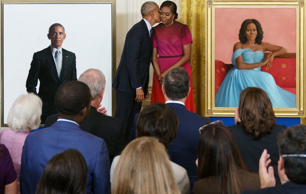 Mantan Presiden AS Barack Obama mencium istrinya, Michelle, saat upacara pembukaan selubung lukisan potret di Gedung Putih, Washington DC, 7 September 2022. 