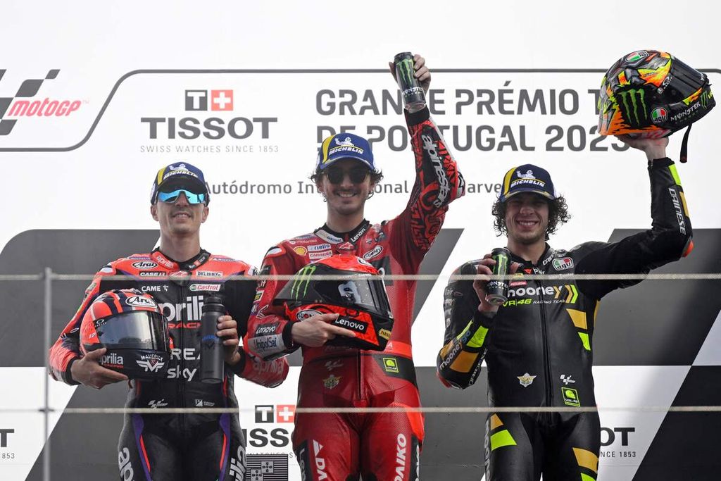 Pebalap tim Ducati Francesco Bagnaia (tengah) merayakan kemenangannya di podium bersama Maverick Vinales (kiri) dan Marco Bezzecchi pada MotoGP seri Portugal di Sirkuit Internasional Algarve, Minggu (26/3/2023). 