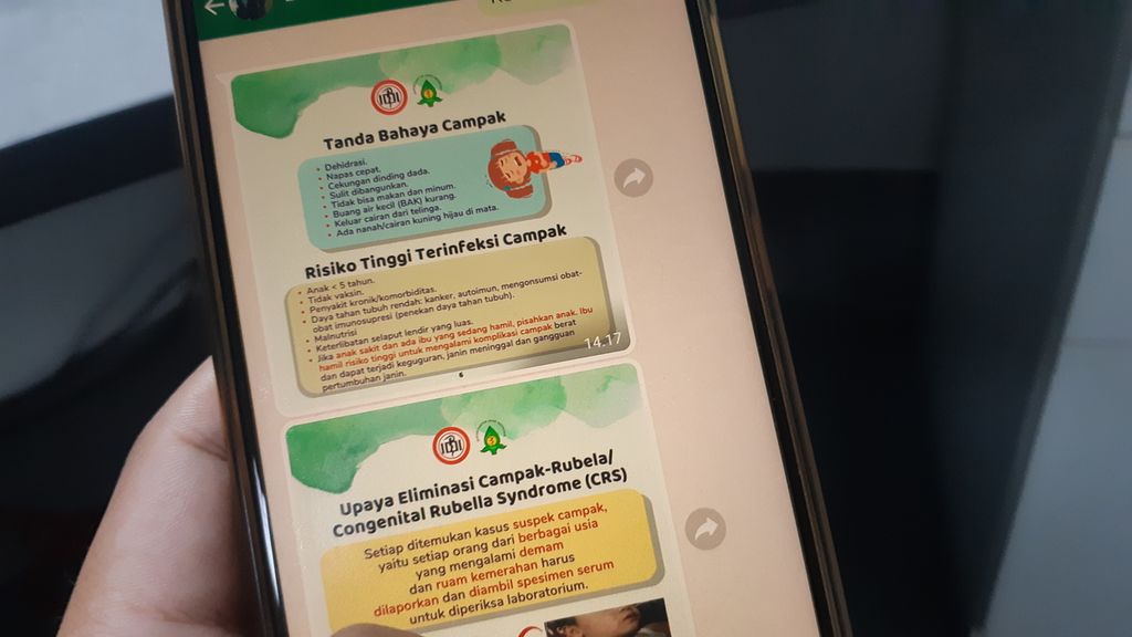 Warga membuka poster digital sosialisasi penyakit campak pada anak yang disebarkan melalui jaringan komunikasi di ponsel, di Jakarta, Kamis (26/1/2023).