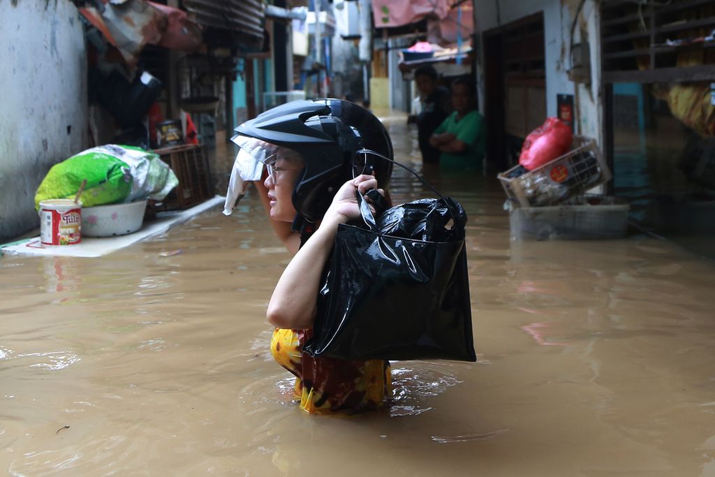 Seorang warga Kebon Pala, Kampung Melayu, Jakarta Timur, tengah menyelamatkan beberapa dokumen penting miliknya, Senin (10/10/2022). Akibat debit air di Kali Ciliwung naik, kampung Kebon Pala, terendam banjir sejak dini hari tadi. ketinggian, air pada pukul 08.00 masih sekitar 150 sentimeter. 
