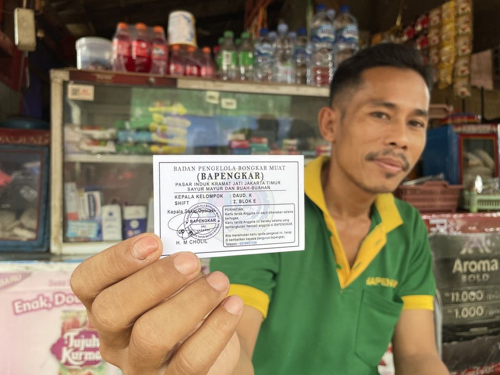 Santibi (43) menunjukkan kartu tanda keanggotaan Badan Pengelola Bongkar Muat (Bapengkar) di Pasar Induk Kramat Jati, Jakarta Timur, Rabu (8/3/2023). Selain kartu tanda keanggotaan, kuli yang bergabung dengan Bapengkar mendapatkan kaos untuk bekerja.