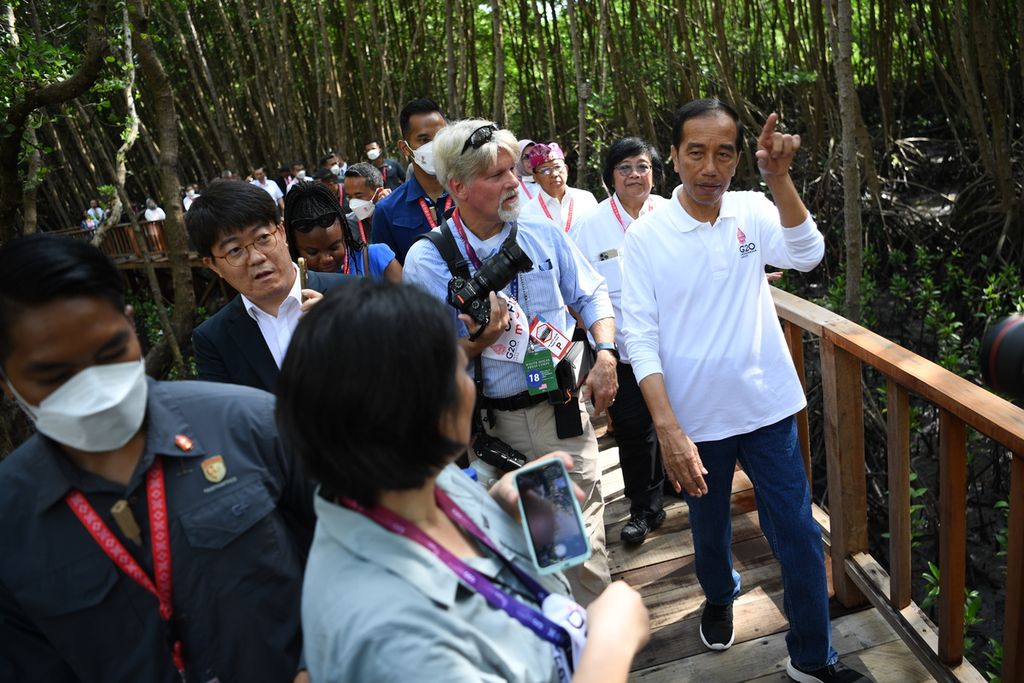 Presiden Joko Widodo (kanan) bersama sejumlah wartawan dalam negeri dan luar negeri mengunjungi kawasan hutan mangrove dalam rangkaian kegiatan KTT G20 di Taman Hutan Raya (Tahura) Ngurah Rai, Denpasar, Bali, Rabu (16/11/2022). 