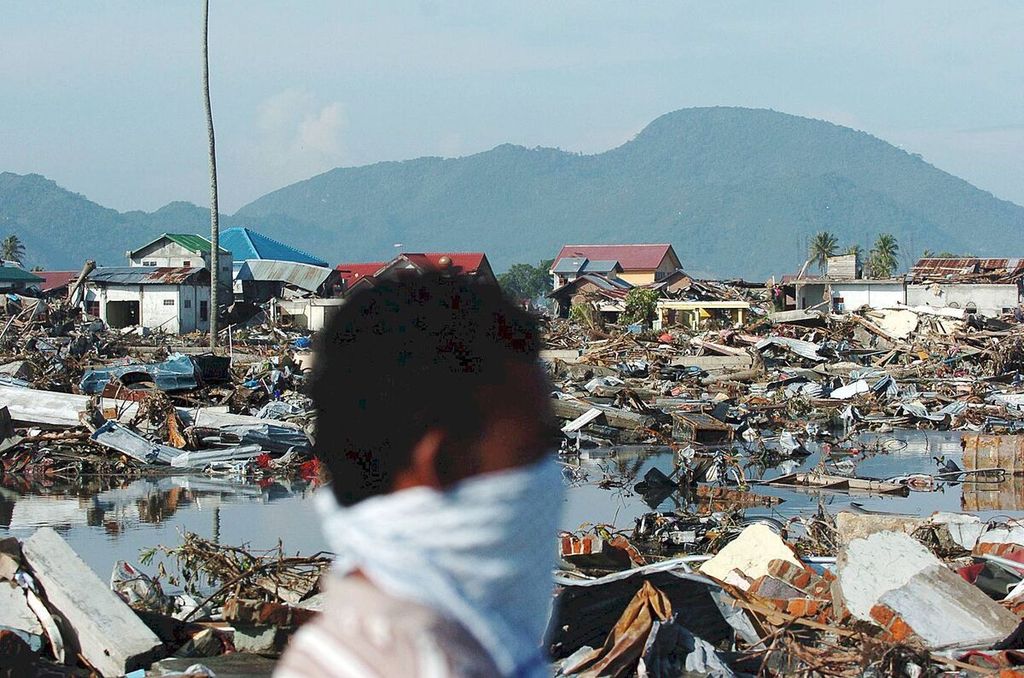 Warga melintas di permukiman yang hancur tersapu gempa dan gelombang tsunami di Lampare Kota, Banda Aceh, Provinsi Nanggroe Aceh Darussalam, Selasa (28/12/2014).