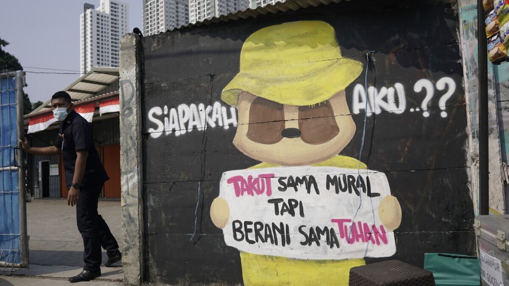 Warga melintasi kritikan terhadap penguasa di kawasan Tanah Abang, Jakarta Pusat, Kamis (9/9/2021). Kritik demokrasi harusnya dijadikan momentum memperbaiki birokrasi bukan dibungkam dengan cara dihapus dan dihilangkan.