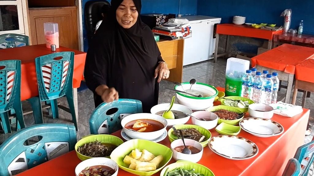 Mama Salma Baya (58) menyiapkan menu papeda dan masakan lainnya di warung miliknya di Daruba, Kabupaten Pulau Morotai, Maluku Utara, akhir Juli 2022.