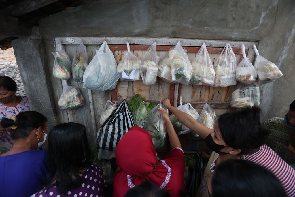 Warga mengambil paket berisi sejumlah bahan makanan yang dibagikan dalam kegiatan cantelan di Kelurahan Bumijo, Jetis, Yogyakarta, Jumat (17/6/2022). Kegiatan berbagi bahan makanan untuk warga yang membutuhkan tersebut mulai berlangsung sejak awal pandemi Covid-19 dan terus rutin dilakukan hingga saat ini.