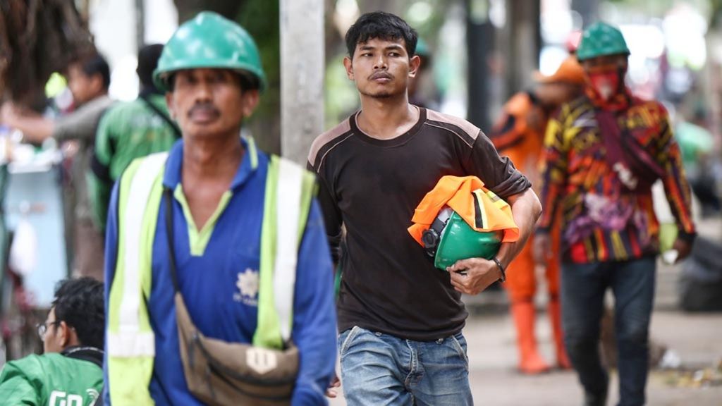 Pekerja meninggalkan lokasi proyek properti saat jam istirahat di kawasan Kuningan, Jakarta, Sabtu (23/3/2019).