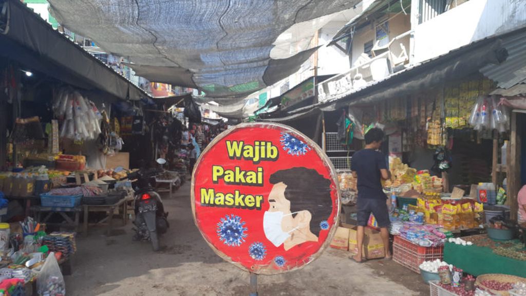 Peringatan wajib mengenakan masker terpasang di dalam kompleks Pasar Inpres Naikoten, Kota Kupang, NTT, pada Rabu (21/7/2021). Tampak seorang pedagang (membelakangi), tidak mengenakan masker.