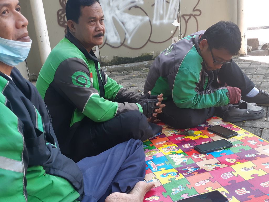Tiga pengemudi ojek daring sedang menunggu pesanan di kawasan Kemang, Jakarta Selatan, Rabu (6/4/2022). Mereka harus mengadu nasib mencari peruntungan di tengah tidak stabilnya ekonomi.