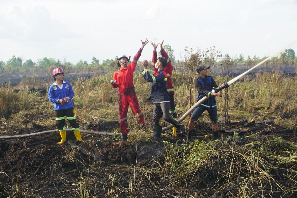 Petugas gabungan dari BPBD Kota Palangkaraya dan Manggala Agni serta sukarelawan pemadam kebakaran berebut botol air minum di sela-sela pemadaman lahan yang terbakar di Jalan Danau Rangas, Kota Palangkaraya, Kalimantan Tengah, awal Oktober 2020.