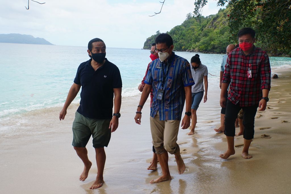 Menteri Pariwisata dan Ekonomi Kreatif Sandiaga Uno (depan kanan) berjalan di pasir Pantai Pulisan ketika mengunjungi Desa Marinsow yang masuk area Kawasan Ekonomi Khusus Likupang, Minahasa Utara, Sulawesi Utara, Sabtu (6/3/2021).