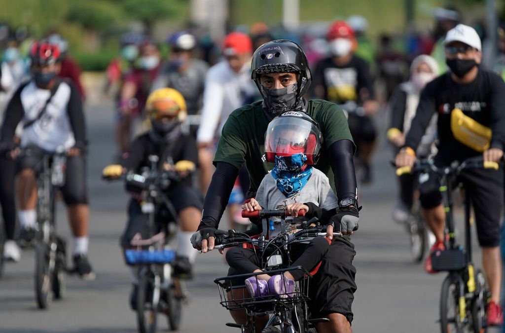 Seorang memboncengkan anak saat sepedaan di hari libur akhir pekan di Bundaran Hotel Indonesia, Jakarta, awal Oktober 2020.