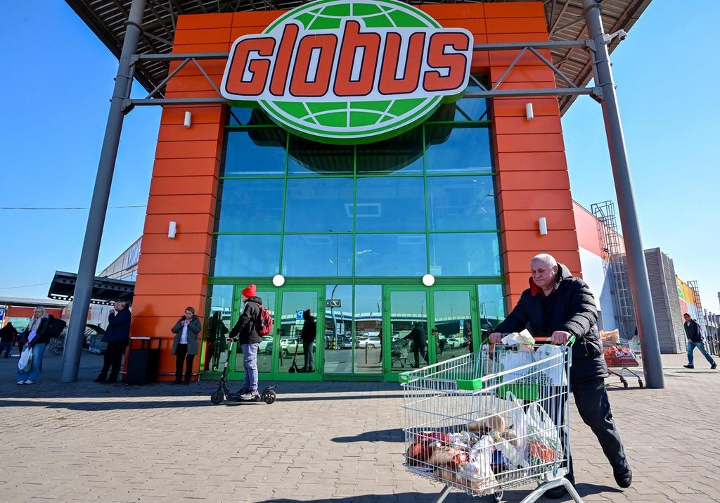 Seorang warga membawa barang-barang yang baru saja ia beli dari retail makanan Globus, di Kota Klimovsk, Rusia (19/3/2022). Sejumlah korporasi dunia menjatuhkan sanksi kepada Moskwa yang membuat warga Rusia cemas.