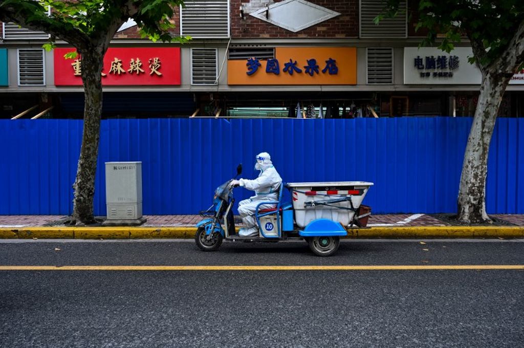 Seorang pekerja yang mengenakan alat pelindung diri berkendara di sebuah ruas jalan selama penguncian Covid-19 di distrik Jing'an, Shanghai , Minggu (29/5/2022). 