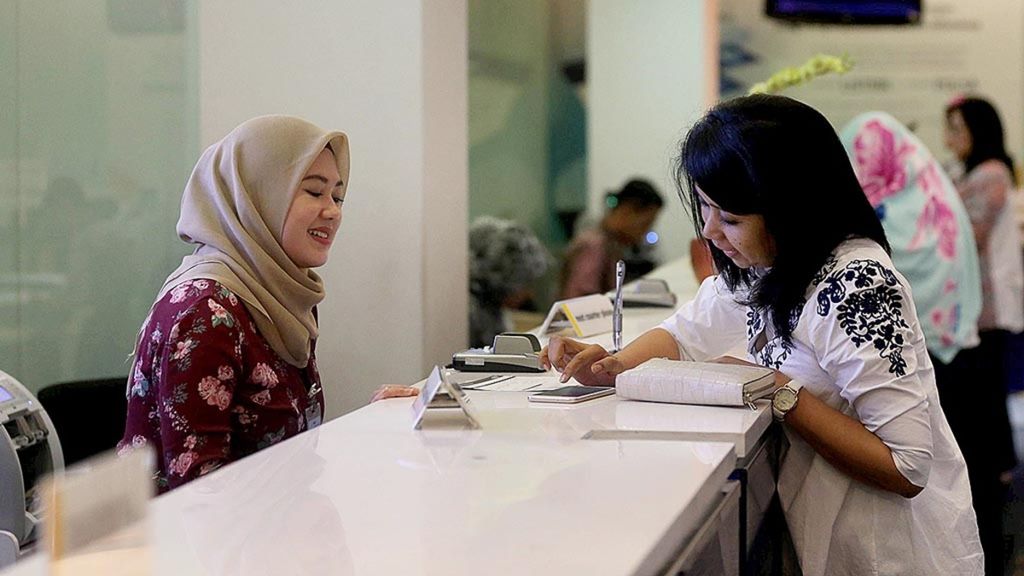 Petugas teller Bank Mandiri melayani nasabah di kantor cabang Plaza Mandiri, Jakarta, Jumat (11/8/2017). 