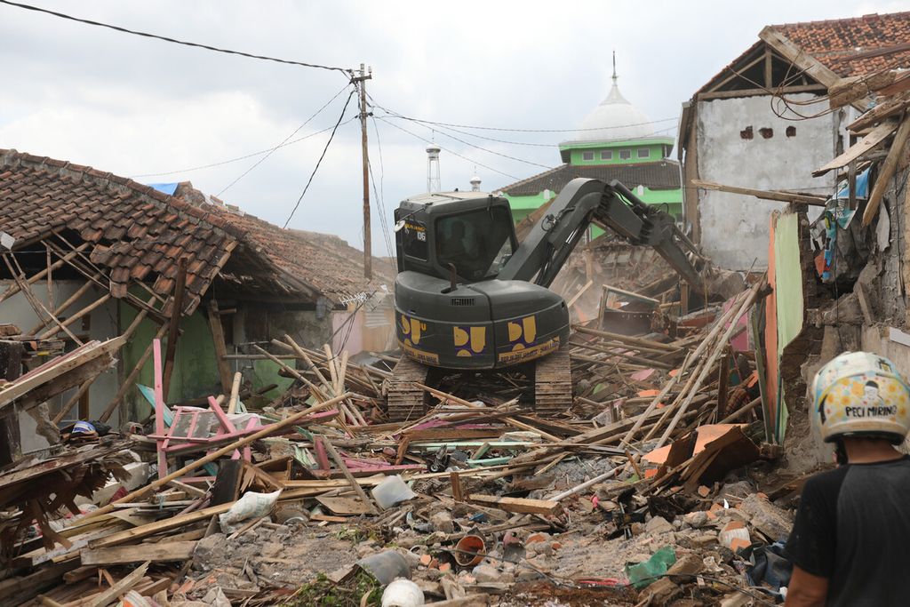 Ekskavator digunakan untuk membersihkan area dari puing bangunan rumah warga di lokasi gempa di Kampung Wargaluyu, Desa Nagrak, Kecamatan Cianjur, Kabupaten Cianjur, Jawa Barat, Minggu (4/12/2022). 