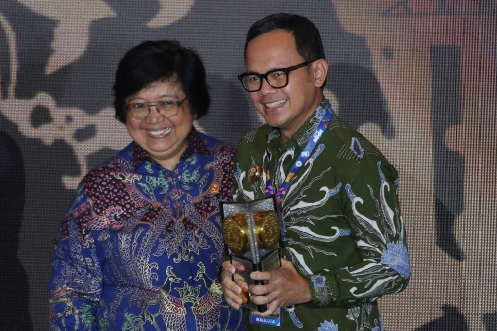 Menteri Lingkungan Hidup dan Kehutanan Siti Nurbaya menyerahkan piala Adipura kepada Wali Kota Bogor Bima Arya.
