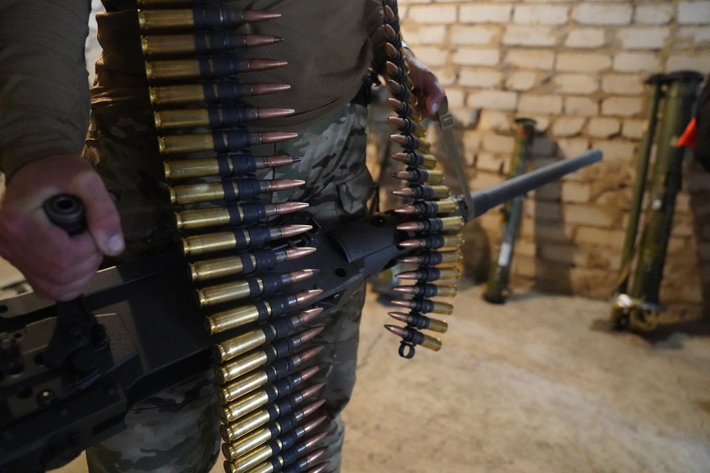Seorang milisi membawa senapan mesin kaliber .50 Browning di sebuah gudang senjata di bagian selatan Ukraina, Rabu (22/6/2022). Perang Ukraina-Rusia masih terus berkecamuk di bagian timur dan selatan Ukraina lewat pertempuran artileri dan serangan rudal. 