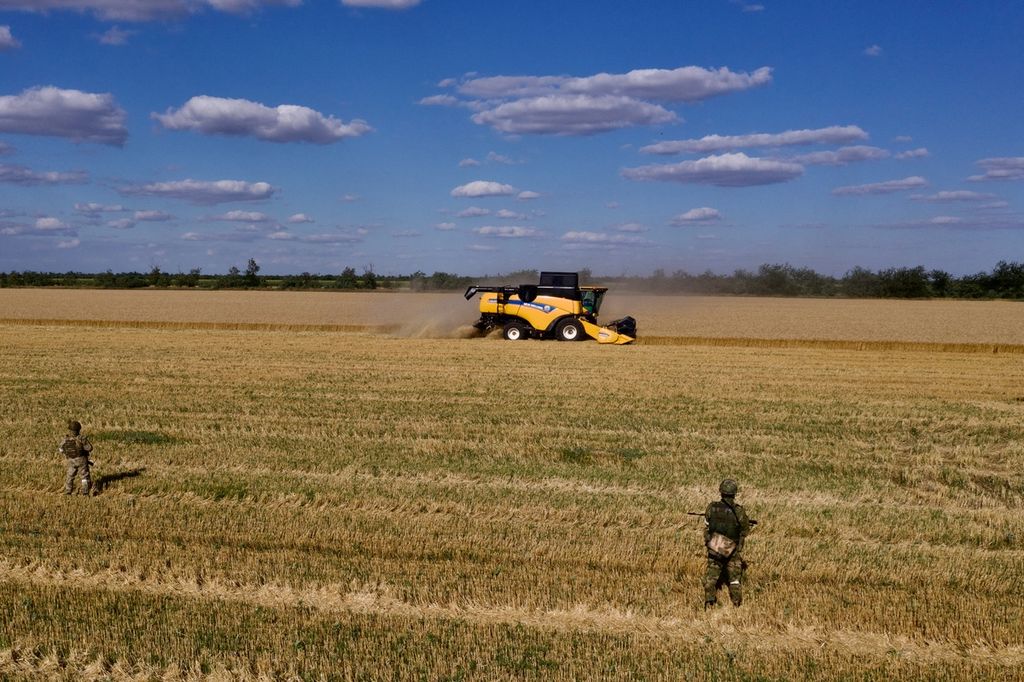 Dalam foto udara yang diambil pada 14 Juli 2022, prajurit Rusia berjaga di ladang saat petani memanen gandum di dekat Melitopol, wilayah Zaporizhzhia, di tengah aksi militer Rusia yang sedang berlangsung di Ukraina.