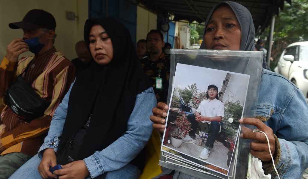 Rini Hanifah (43) memegang foto anaknya, Agus Rainsyah, yang menjadi korban dalam Tragedi Kanjuruhan dalam sidang perdana kasus Tragedi Kanjuruhan di Pengadilan Negeri Surabaya, Jawa Timur, Senin (16/1/2023). Sidang dilakukan secara daring dengan diikuti para terdakwa dari di dalam Rutan Polda Jatim. Lima tersangka kasus Tragedi Kanjuruhan yang akan diadili adalah Ketua Panpel Arema FC Abdul Haris, Security Officer Suko Sutrisno, Danki 3 Brimob Polda Jatim Ajun Komisaris  Has Darmawan, Kabag Ops Polres Malang Komisaris  Wahyu Setyo Pranoto, dan Kasat Samapta Polres Malang Ajun Komisaris Bambang Sidik Achmadi.