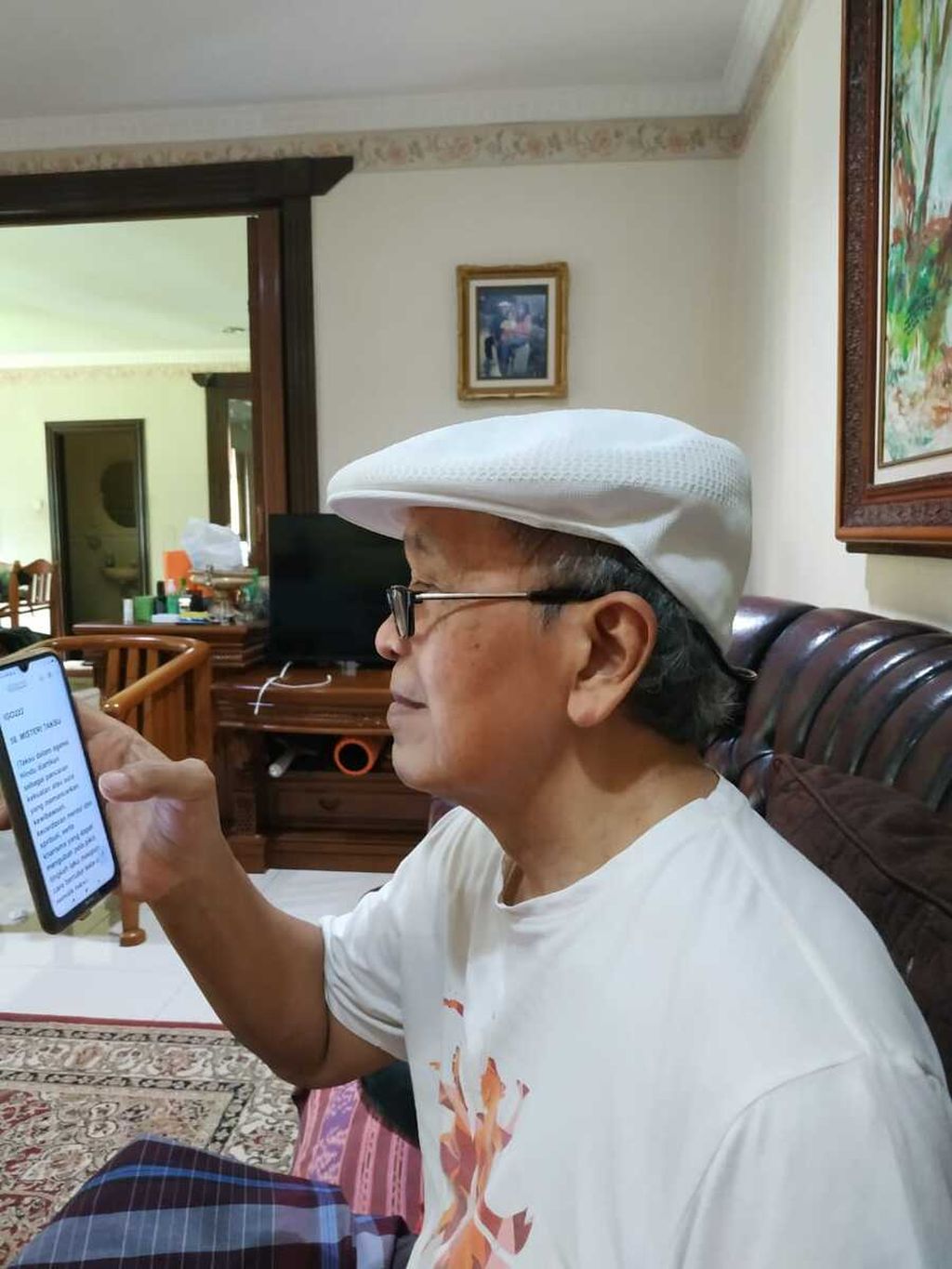 Sastrawan Putu Wijaya (78) sedang menulis di telepon selular dengan hanya menggunakan jempol tangan kanan, Rabu (2/3/2022).