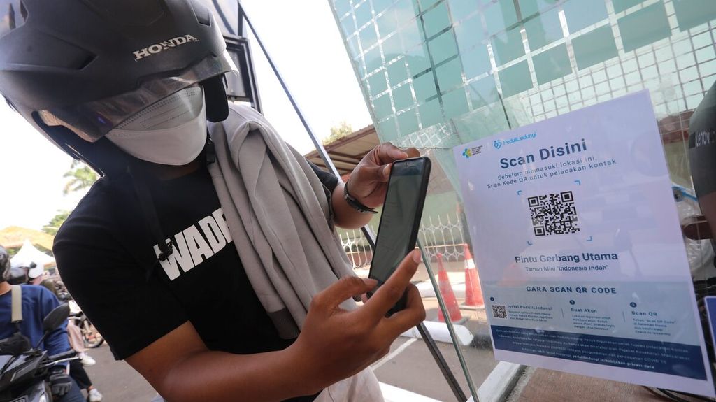 Petugas menunjukkan kode QR yang harus dipindai pengunjung dengan aplikasi Peduli Lindungi sebelum masuk untuk wisata di Taman Mini Indonesia Indah (TMII), Jakarta Timur, Jumat (17/9/2021).