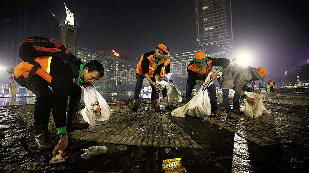 Petugas kebersihan  membersihkan sampah sisa perayaan pergantian tahun 2017 ke 2018 di kawasan Bundaran Hotel Indonesia, Jakarta, Selasa (1/1) dini hari. Meski dalam gegap gempita perayaan Tahun Baru, mereka tetap bertugas melayani dan menjaga kebersihan kota.