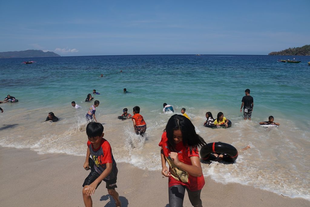 Anak-anak berlari menghindari ombak, Sabtu (9/11/2019), di Pantai Pulisan, Likupang Timur, Minahasa Utara, Sulawesi Utara. Pantai itu merupakan destinasi wisata utama di wilayah calon Kawasan Ekonomi Khusus (KEK) Likupang.
