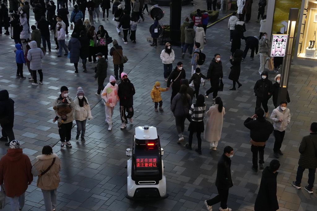 Robot polisi berpatroli di dekat kerumunan warga yang kembali memenuhi mal setelah pelonggaran pembatasan pandemi di Beijing, China, Minggu (1/1/2023). Sambil berkeliling, robot itu mengatakan, "Saya sedang berpatroli. Harap berhati-hati dan memberi jalan". 