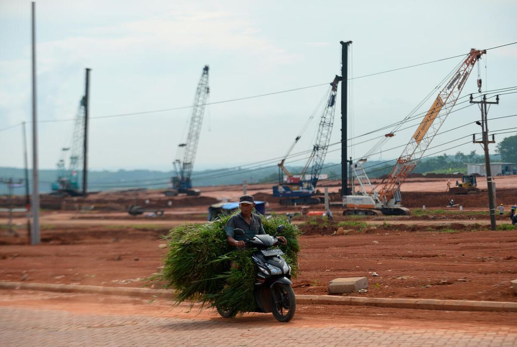 Warga membawa rumput pakan ternaknya melintas di sekitar proyek pembangunan infrastruktur kawasan industri di Kecamatan Tulis, Kabupaten Batang, Jawa Tengah, 13 Juni 2022. 