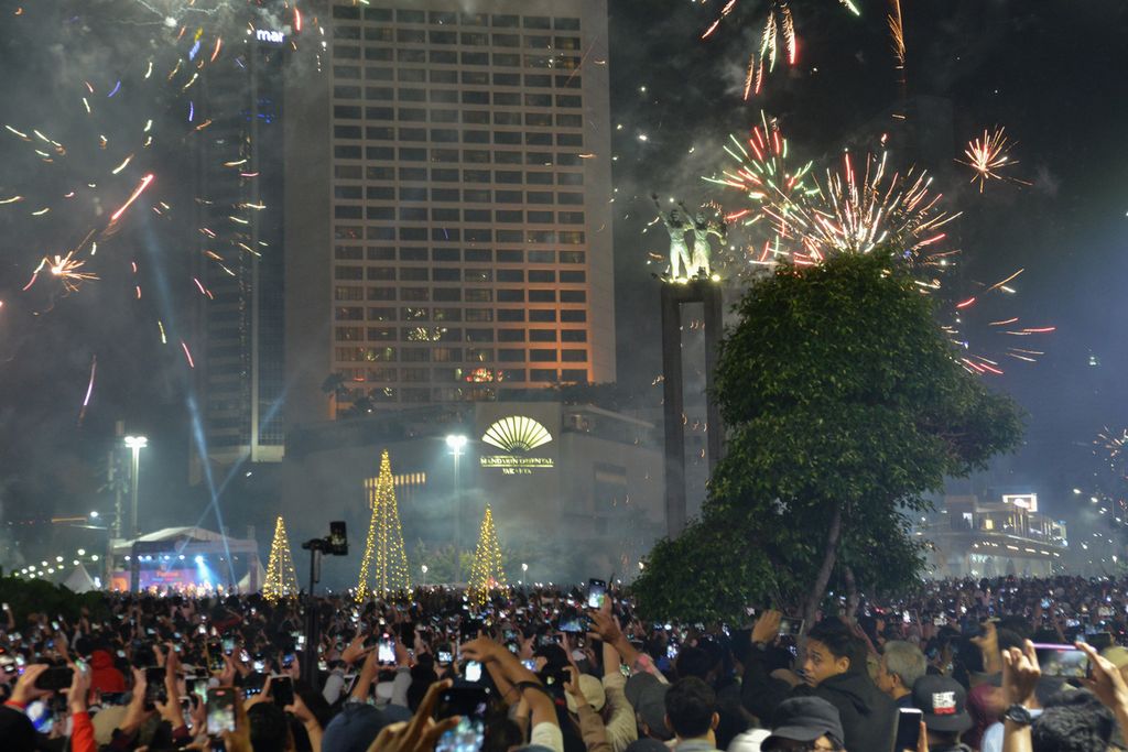 Warga menyaksikan pertunjukan kembang api di sekitaran Bundaran Hotel Indonesia (HI), Jakarta Pusat, Minggu (1/1/2023). Bundaran HI menjadi salah satu kawasan yang dipilih warga untuk merayakan pergantian Tahun Baru 2023. Tidak hanya kembang api, warga juga disuguhkan penampilan sejumlah penampilan musik di panggung Malam Muda Mudi. 