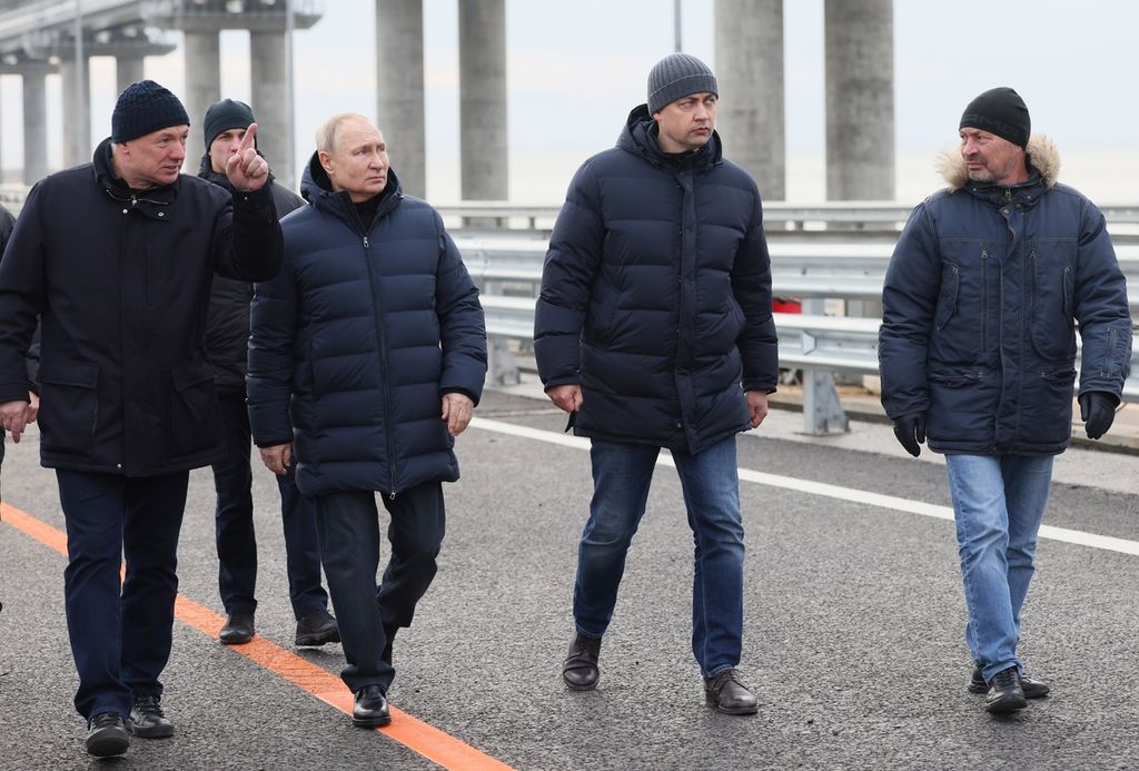 Presiden Rusia Vladimir Putin (ketiga dari kiri) mendengarkan laporan Wakil Perdana Menteri Marat Khusnullin (kiri) saat meninjau Jembatan Kerch, Senin (5/12/2022). Jembatan Kerch menghubungkan wilayah selatan Rusia dengan Semenanjung Crimea. Pada 8 Oktober, ledakan bom truk terjadi di salah satu bagian jembatan. 