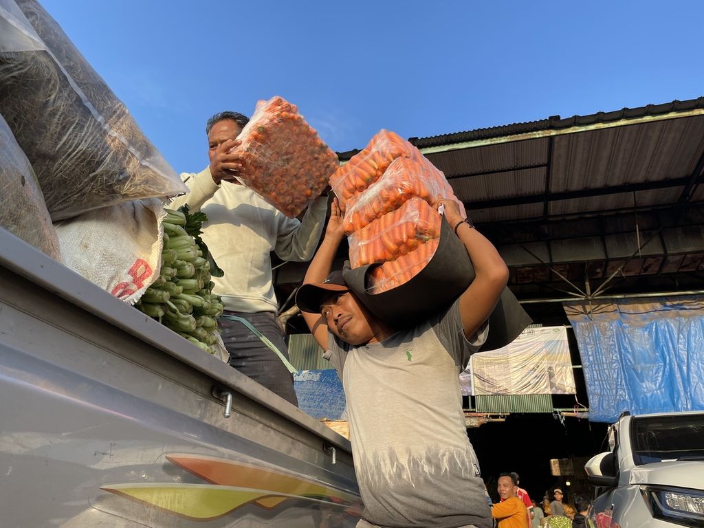 Mistori (43), kuli angkut di Pasar Induk Kramat Jati, memikul wortel dari lapak sayuran menuju pikap pembel di parkiran, Rabu (8/3/2023).
