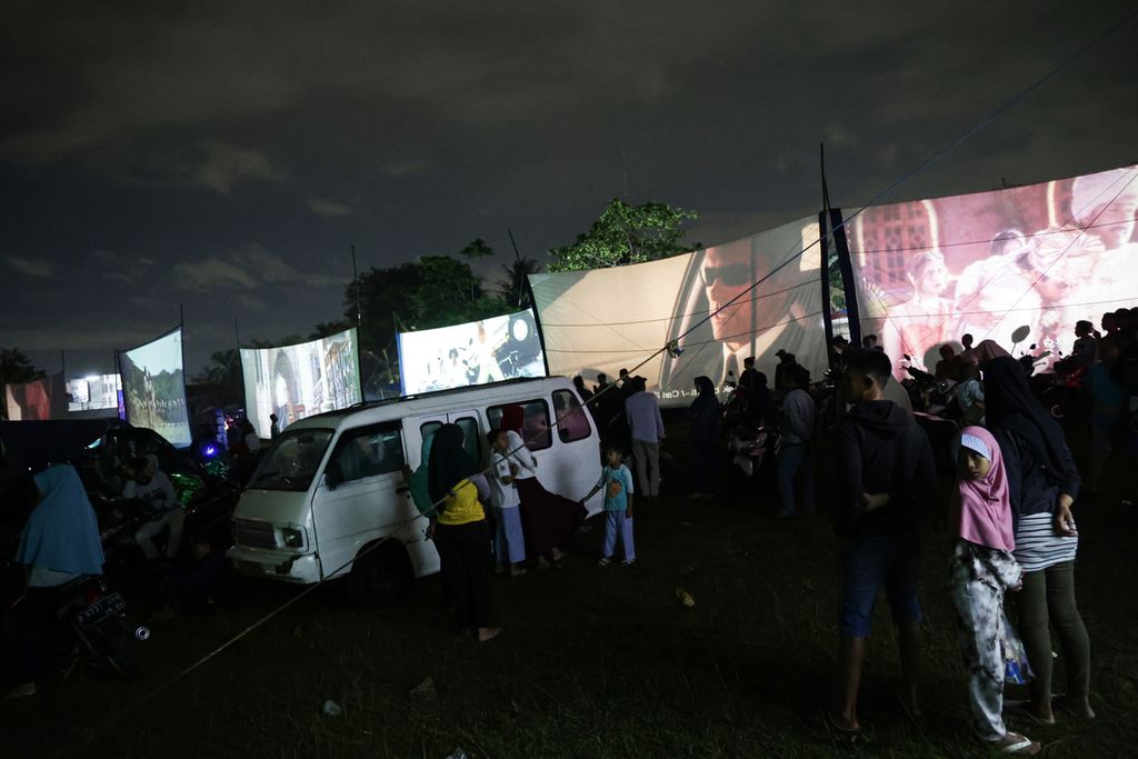 Antusias warga yang menyaksikan film dalam festival layar tancap di lapangan di Babakan, Kecamatan Setu, Tangerang Selatan, Banten, Rabu (18/1/2023) malam. Sebanyak 21 layar tancap memutar film berbagai genre secara bersamaan.
