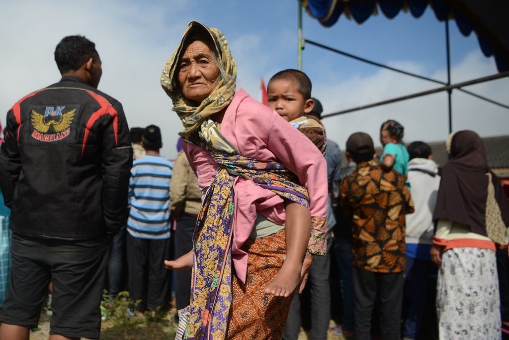 Seorang nenek mengasuh cucunya di Desa Wonolelo, Sawangan, Magelang, Jawa Tengah, Senin (19/8/2019). Berbagai pekerjaan rumah tangga sehari-hari masih kerap menjadi tugas utama para warga lansia di usia senja mereka.